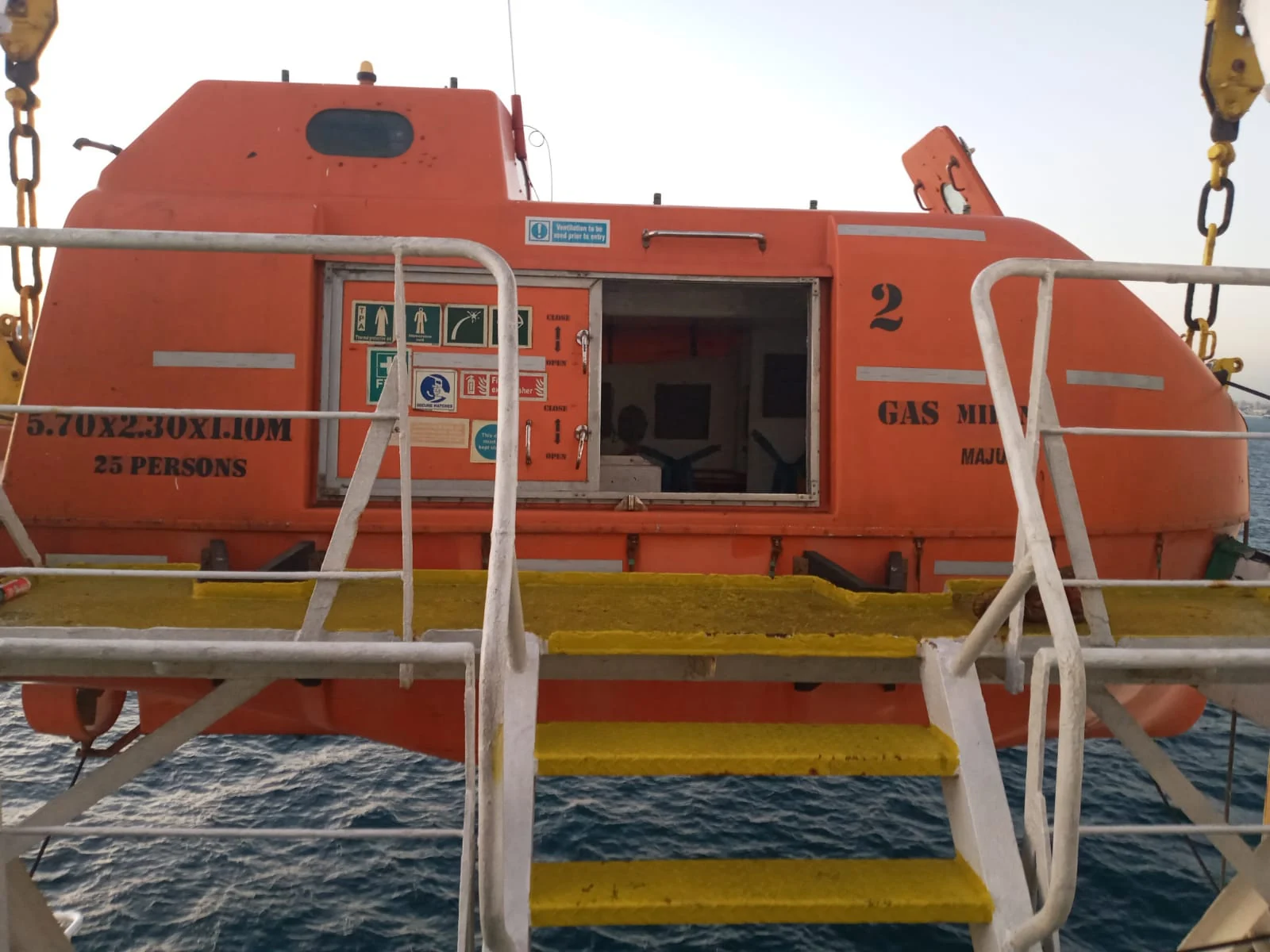 Enclosed lifeboat suspended at its launching system