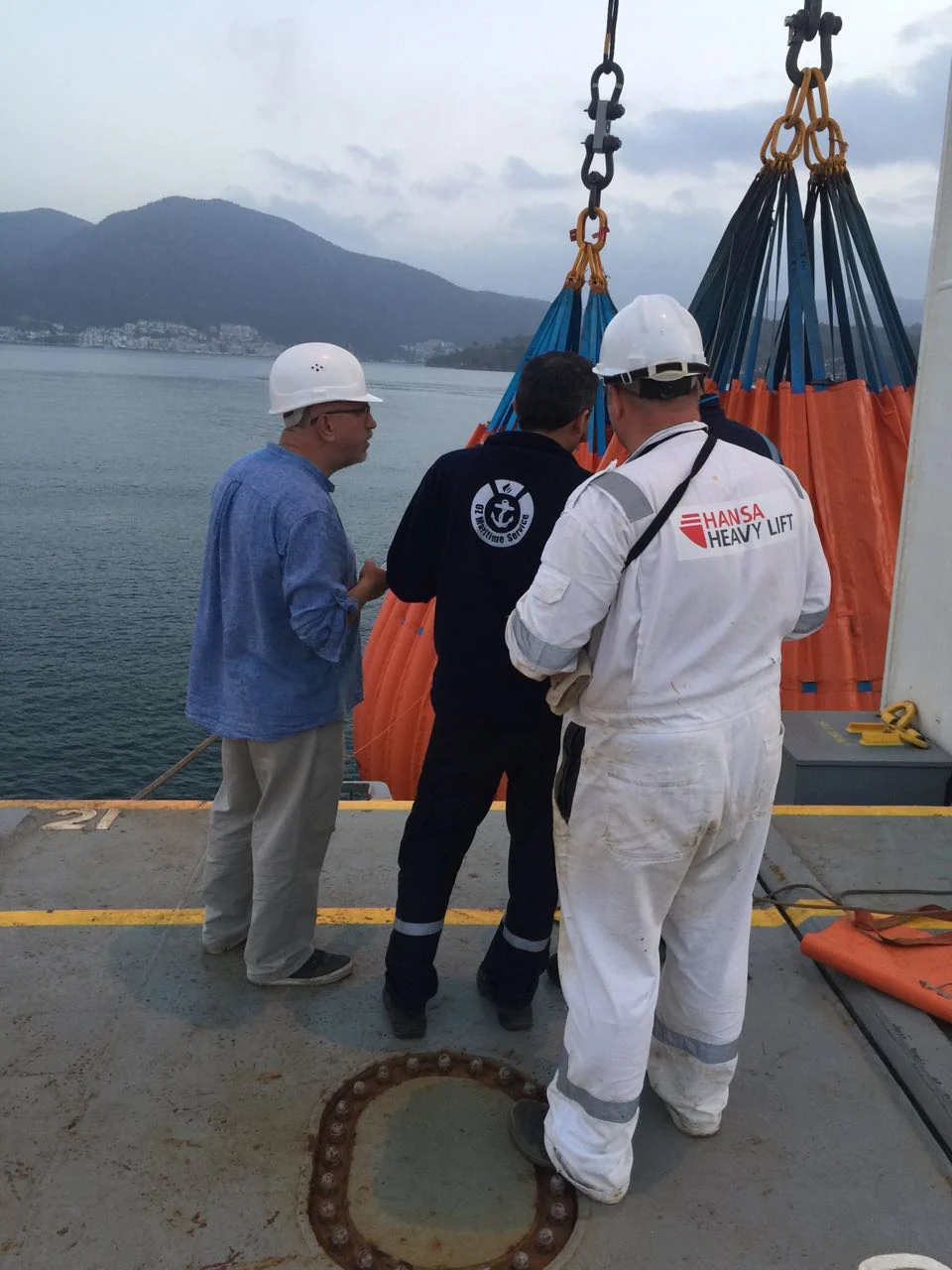 Technicians checking water-bag test equipment together on deck